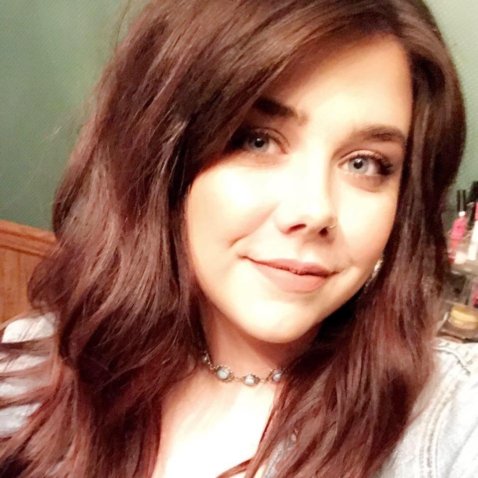 A woman with long brown hair wearing a necklace.